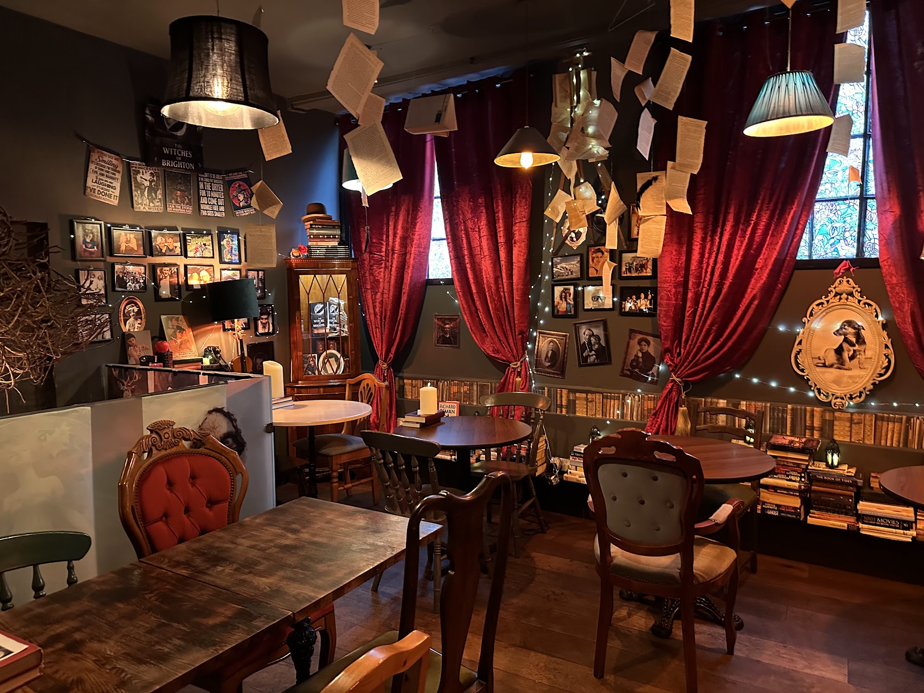 The long dining room at ThewitchEZ with arched leaded windows, candlelight and book pages suspended from the ceiling
